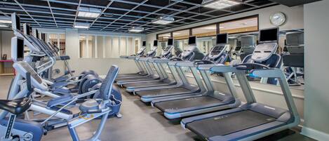 A gym with multiple treadmills, ellipticals, and exercise bikes.