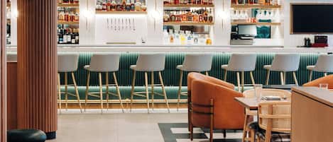 A bar area with multiple seating options, including bar stools and chairs, and a counter with a variety of liquor bottles.