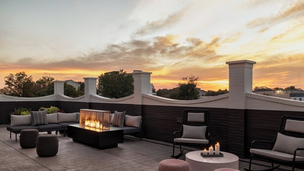 A rooftop patio with a fire feature, seating, and a view of the sunset. - Crowne Plaza Louisville Airport Expo Ctr by IHG (Louisville)