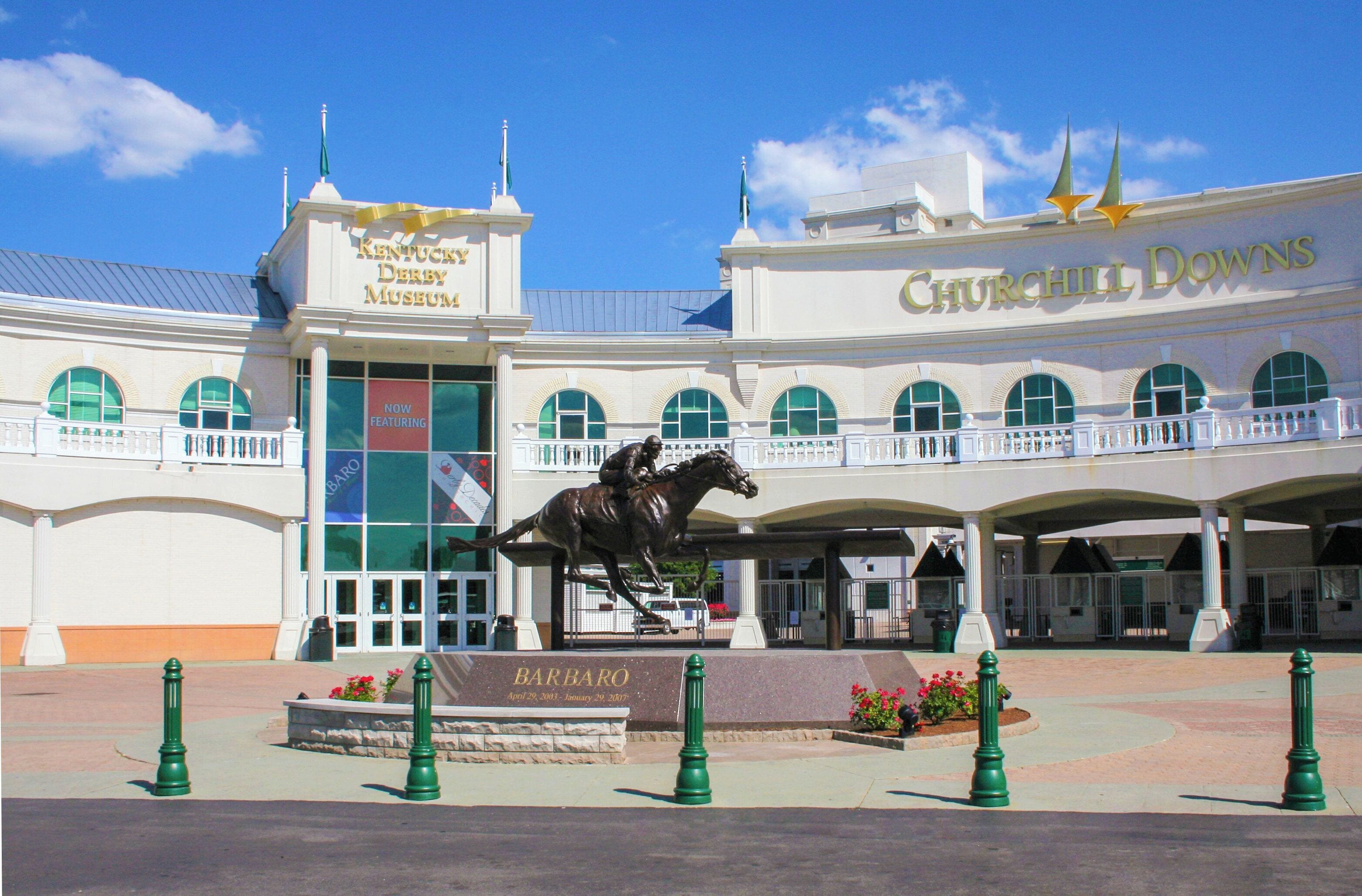 A building with a statue of a man on a horse, a sign for Kentucky Derby Museum, and Churchill Downs.