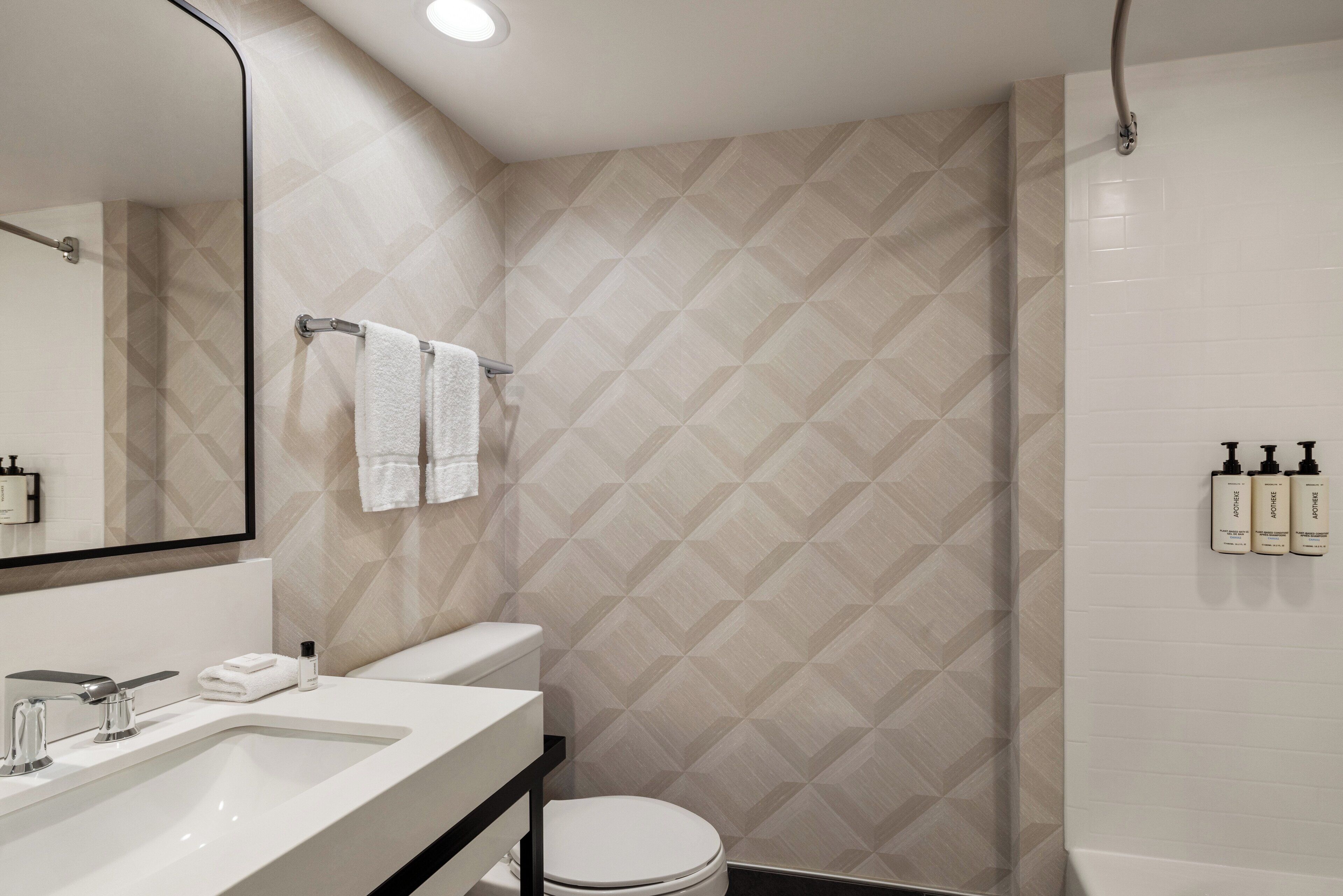 Un baño moderno con un espejo grande, un lavabo, un inodoro y una zona de ducha.