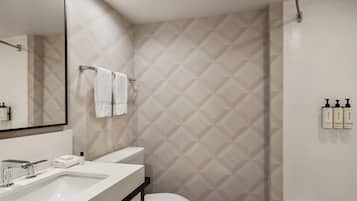 Un baño moderno con un espejo grande, un lavabo, un inodoro y una zona de ducha.