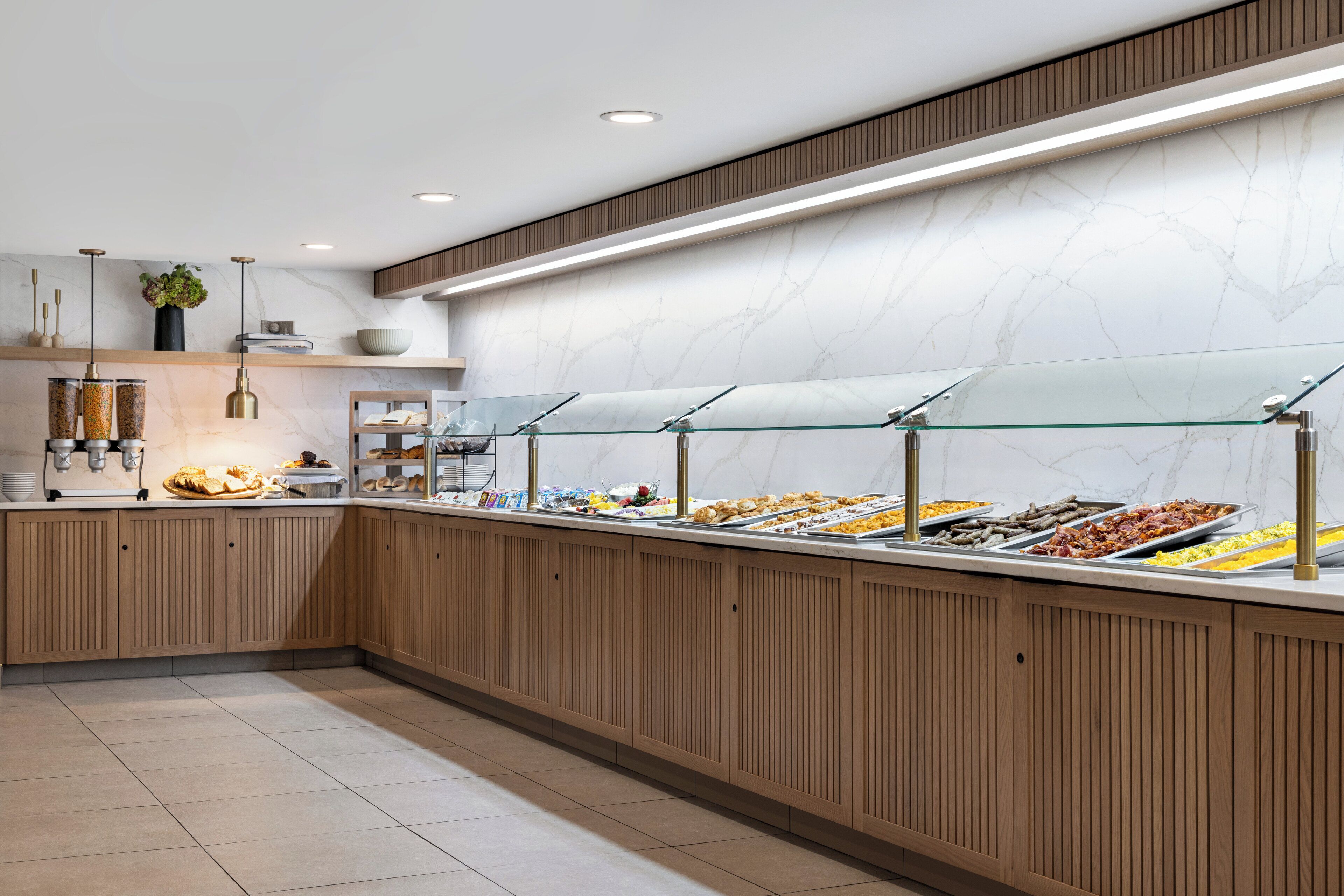 Un espace buffet doté de plusieurs présentoirs de nourriture, de lambris en bois et d’un pare-feu en marbre.