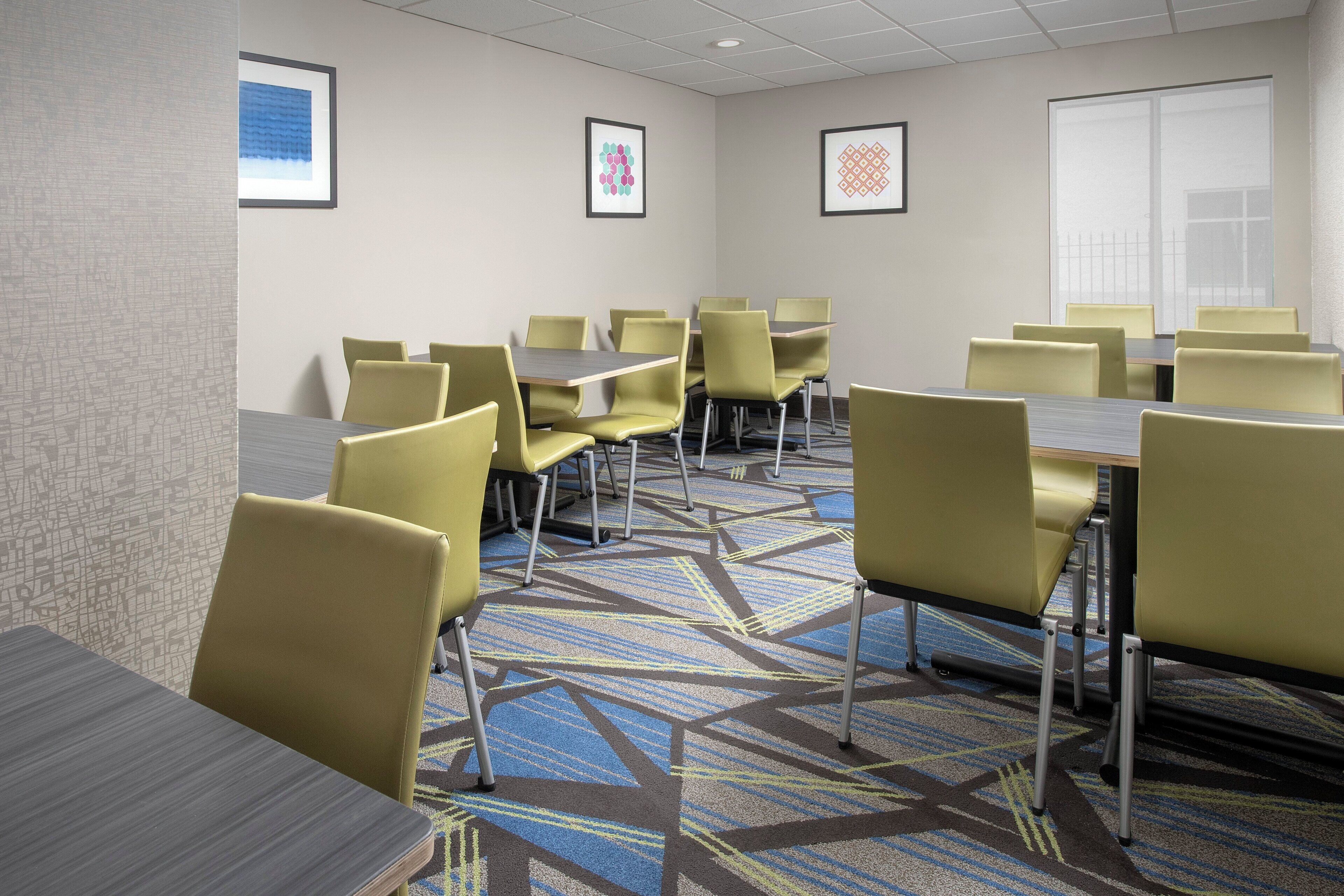 A conference room with tables and chairs, carpeted floor, and framed pictures on the walls.