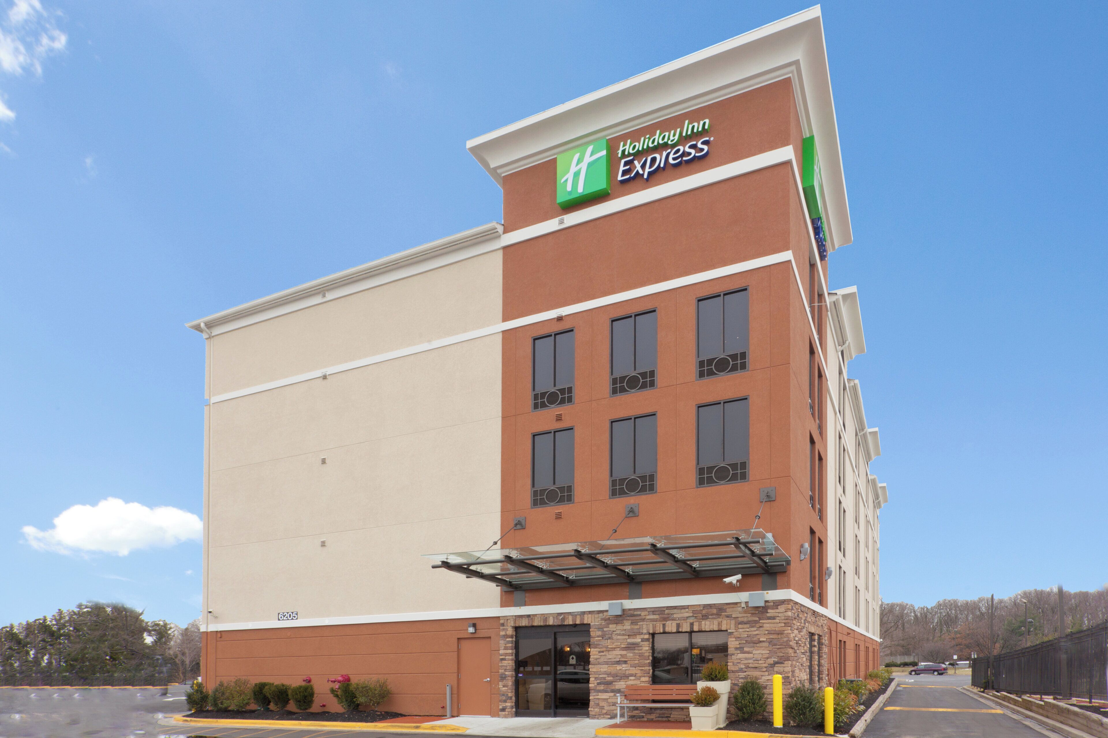 Un hotel Holiday Inn Express con fachada plana, sección inferior de ladrillo y cielo despejado.
