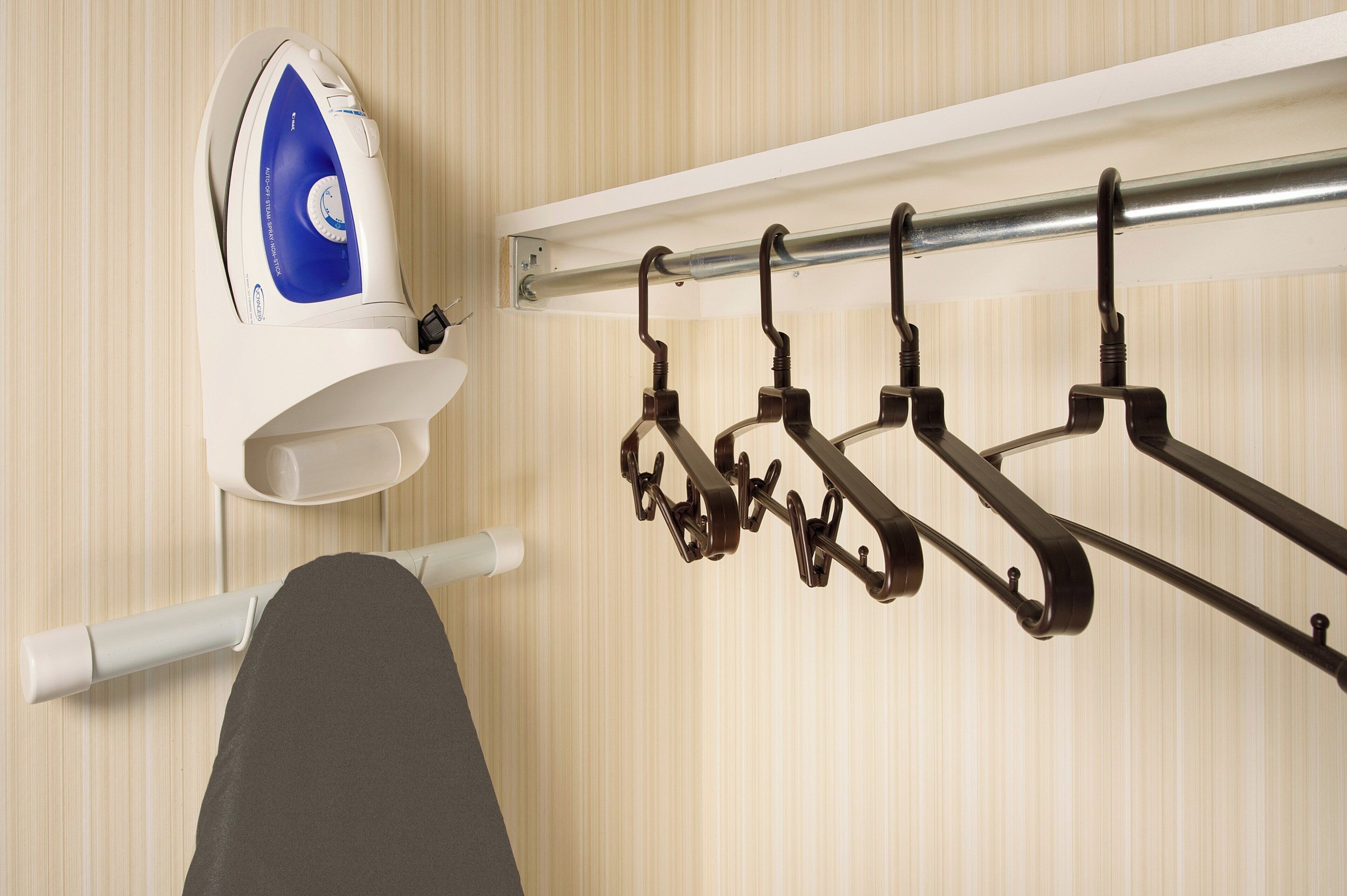 A wall-mounted ironing board with an iron and a metal rack with hooks.
