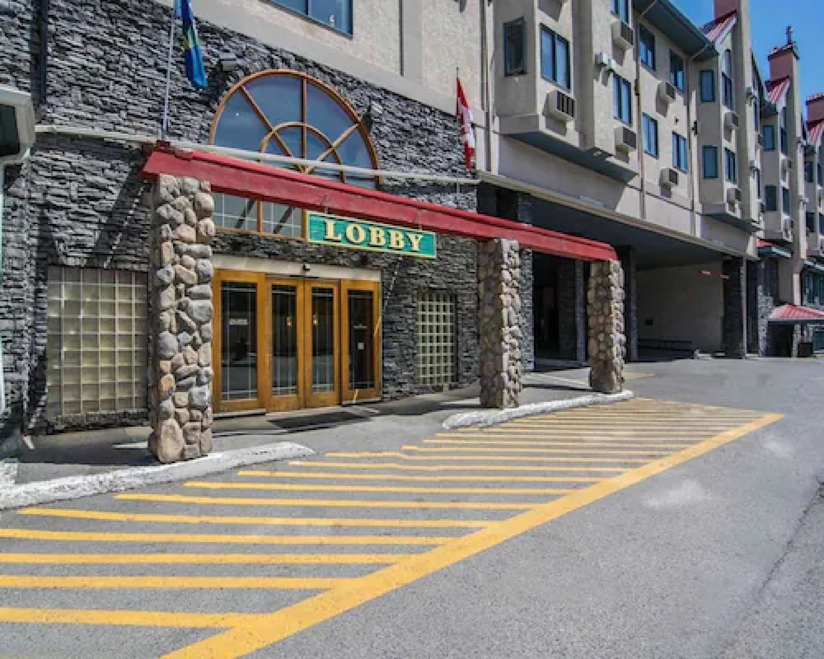 Una entrada de vestíbulo con fachada de piedra, un toldo rojo y un cartel que dice 'Lobby'.