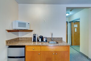 A compact kitchenette with a microwave, coffee maker, and sink.