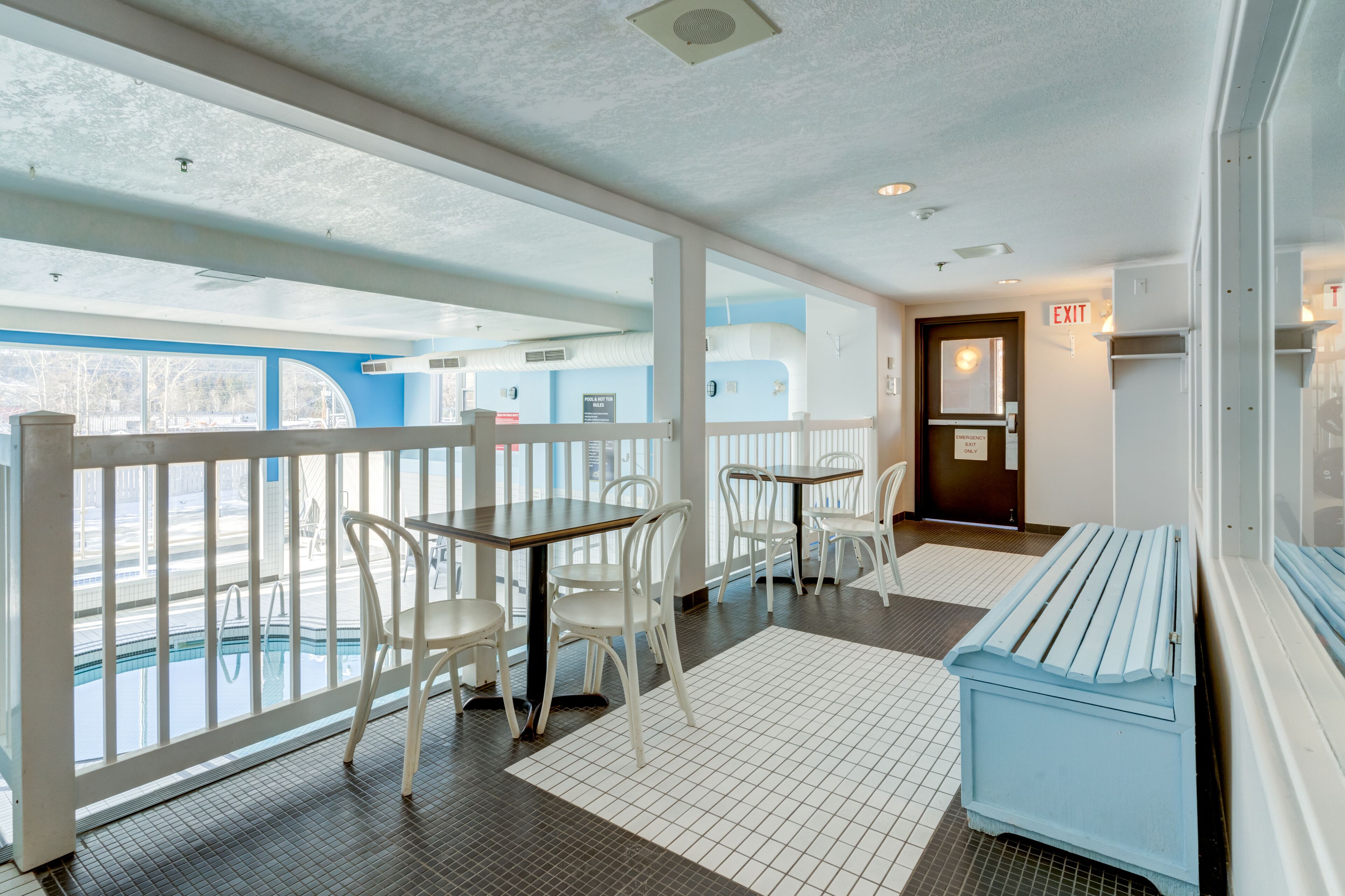 A room with a pool view, white furniture, and an exit sign.
