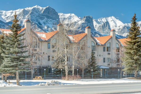 A hotel with a snow-covered mountain backdrop, featuring a traditional architectural style with multiple chimneys and a red roof.