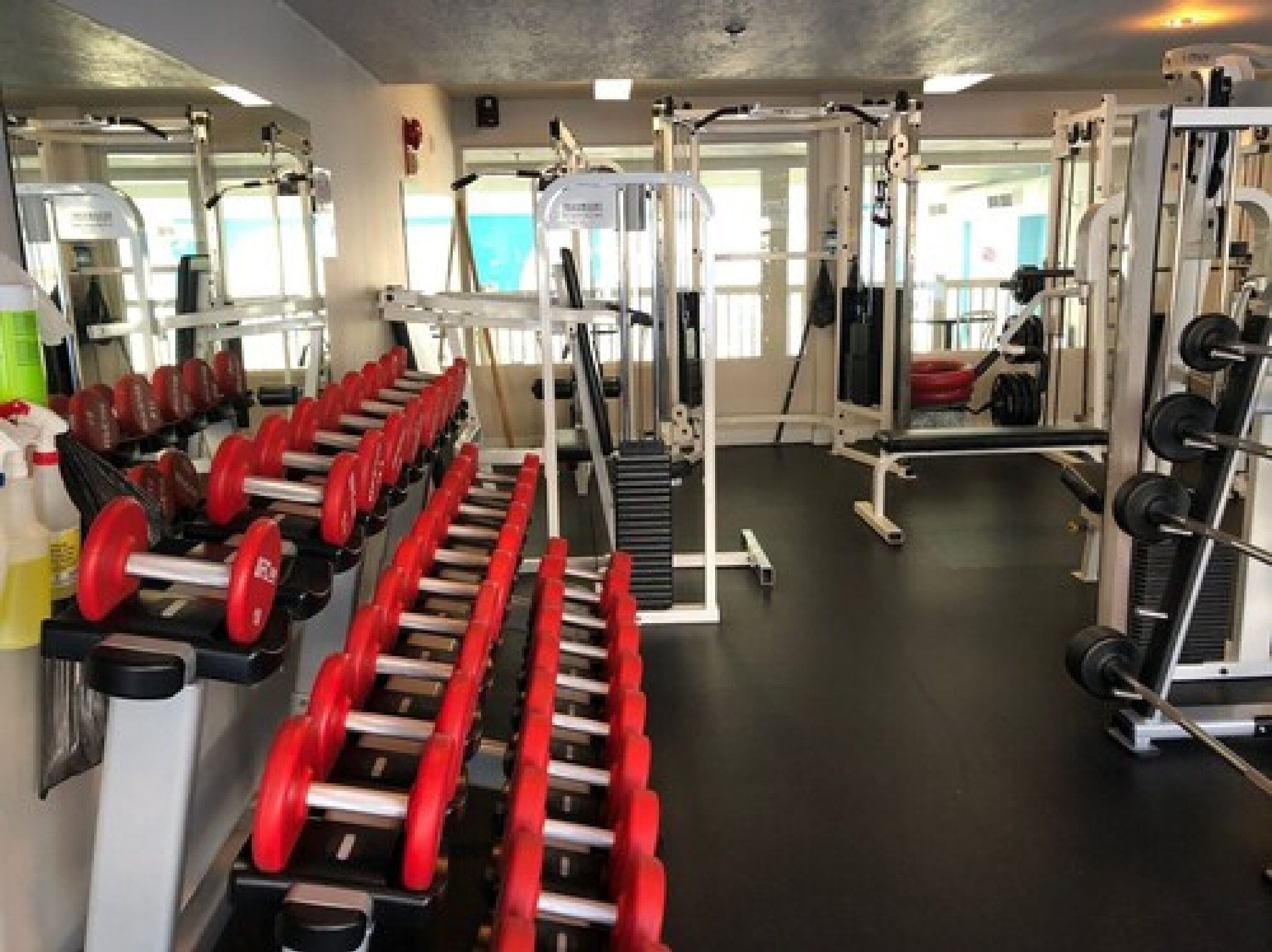 A gym with weightlifting equipment, cardio machines, and mirrors.
