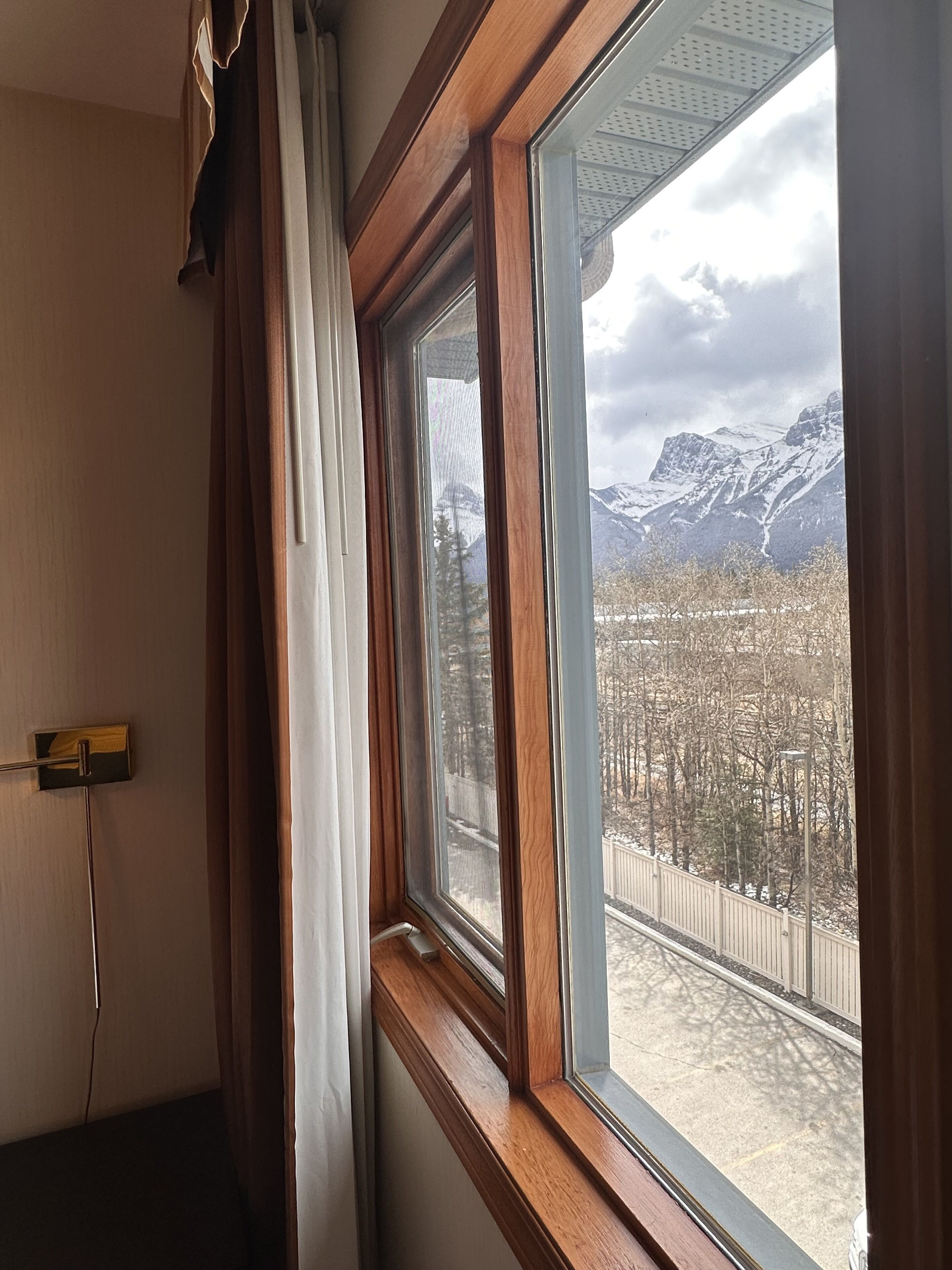 A room with a large window offering a view of snow-covered mountains and a forested area.