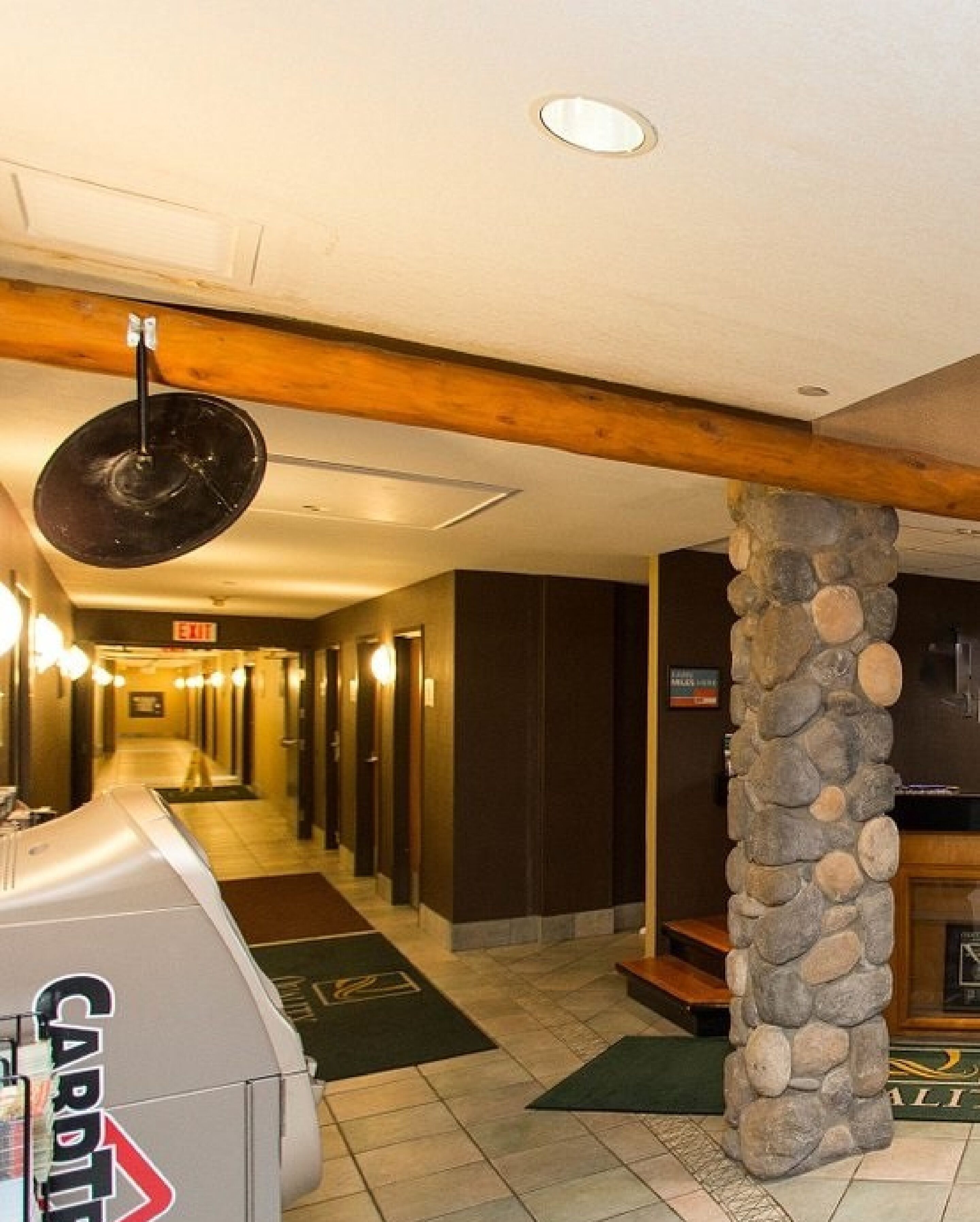 A hotel corridor with a fireplace, stone pillar, and a card table with a logo.