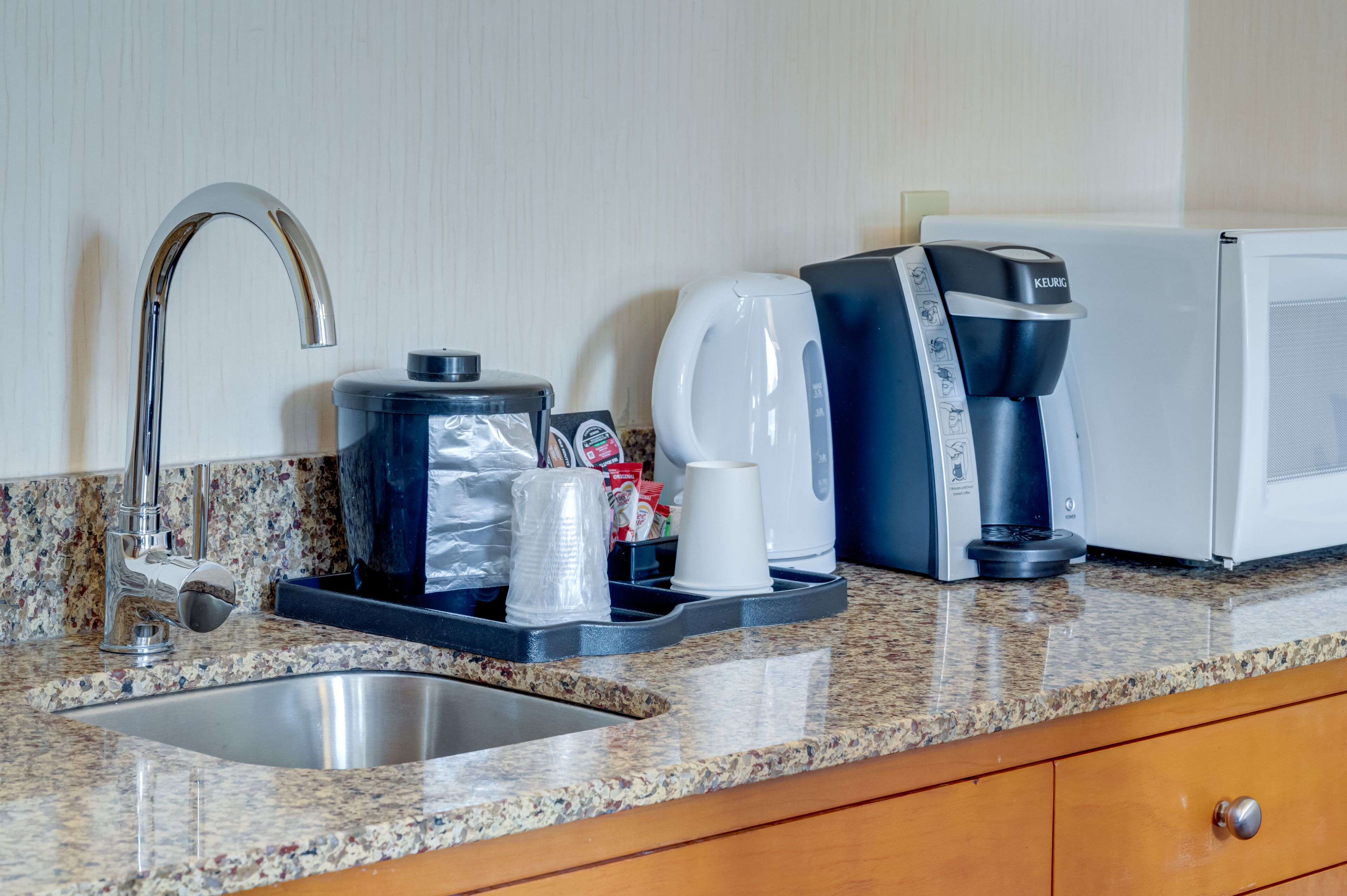 A kitchen counter with a coffee maker, a kettle, and a coffee dispenser.