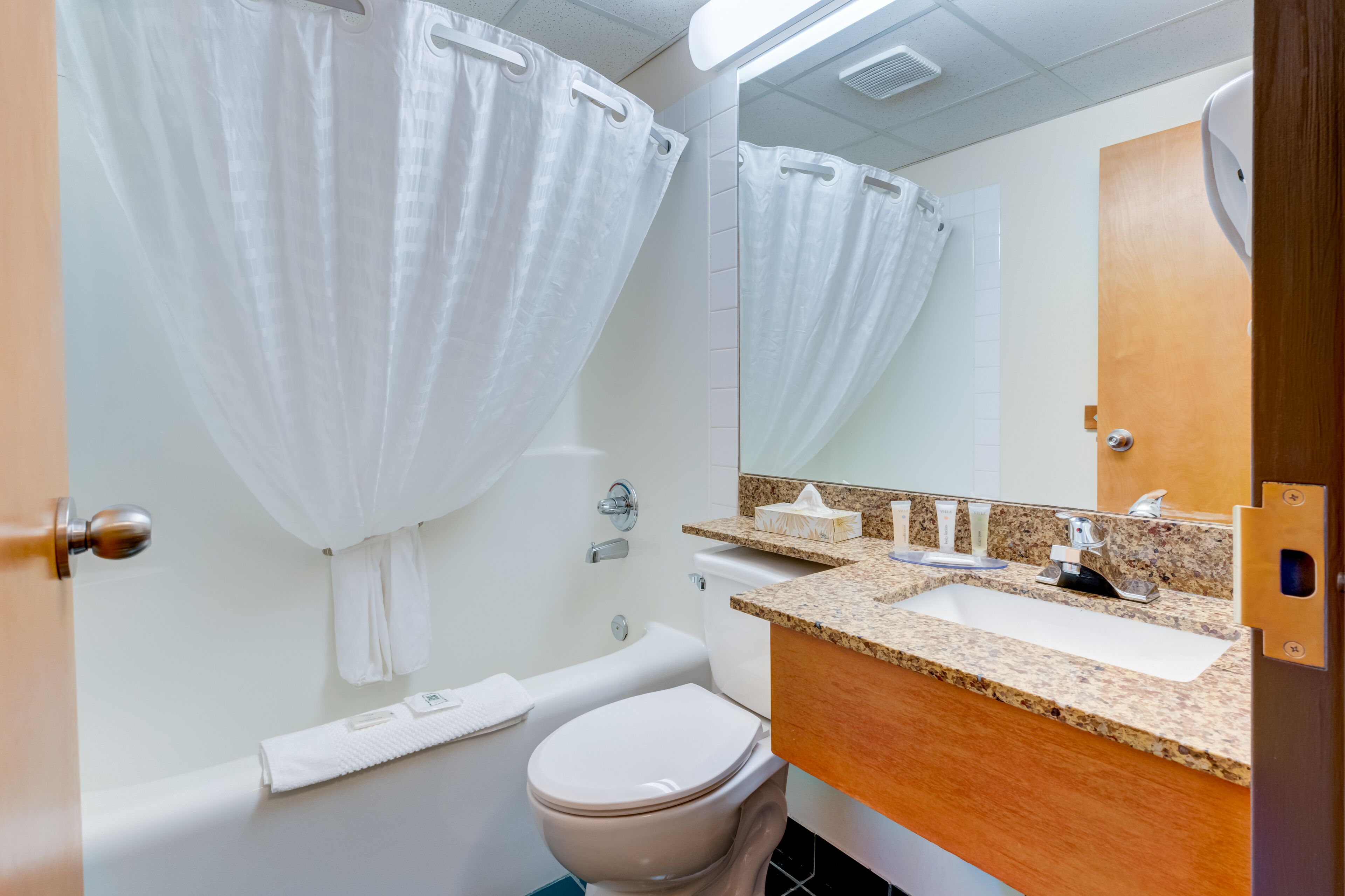 A bathroom with a bathtub, toilet, sink, and a mirror.