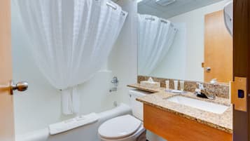 Un baño con bañera, inodoro, lavamanos y espejo.