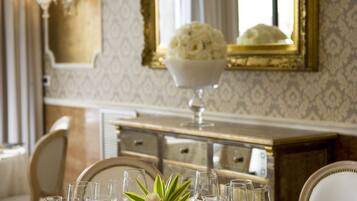 A formal dining table set with multiple wine glasses, forks, and a centerpiece of flowers.