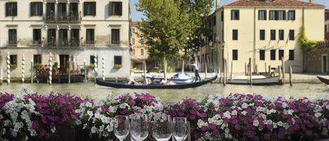 A table set for dining with a view of a canal and buildings in the background.