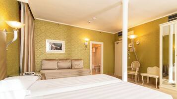 Una habitación de hotel con una cama grande, un sofá, una silla y un armario.