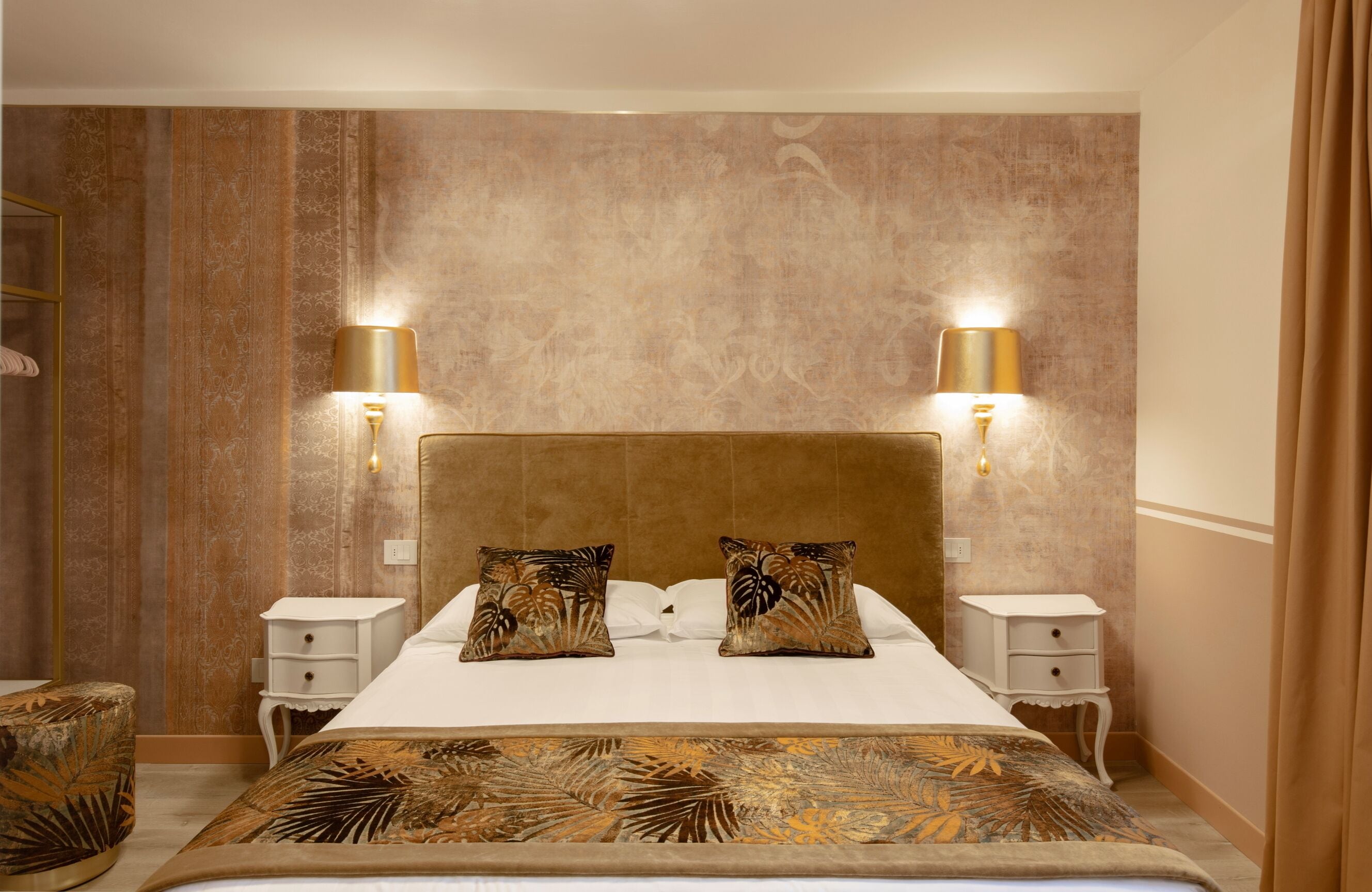 A hotel room with a large bed, two bedside tables, and wall-mounted lamps.