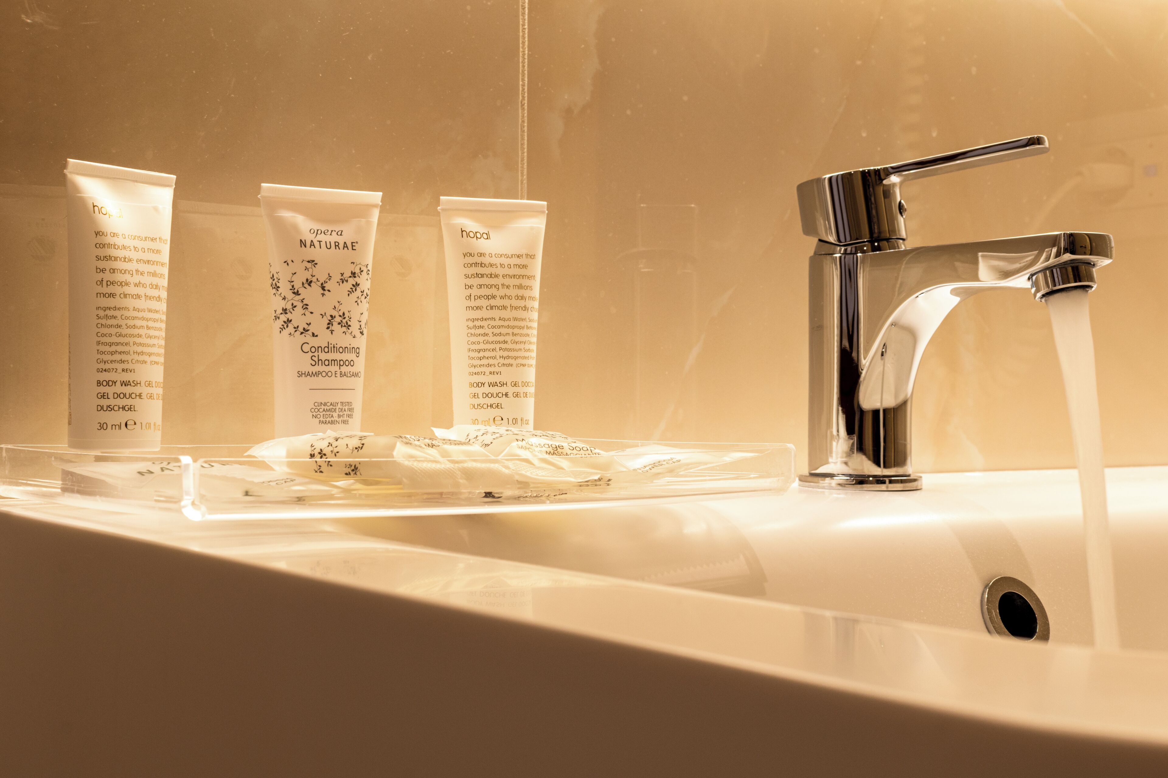 A bathroom sink with three toiletries and a chrome faucet.