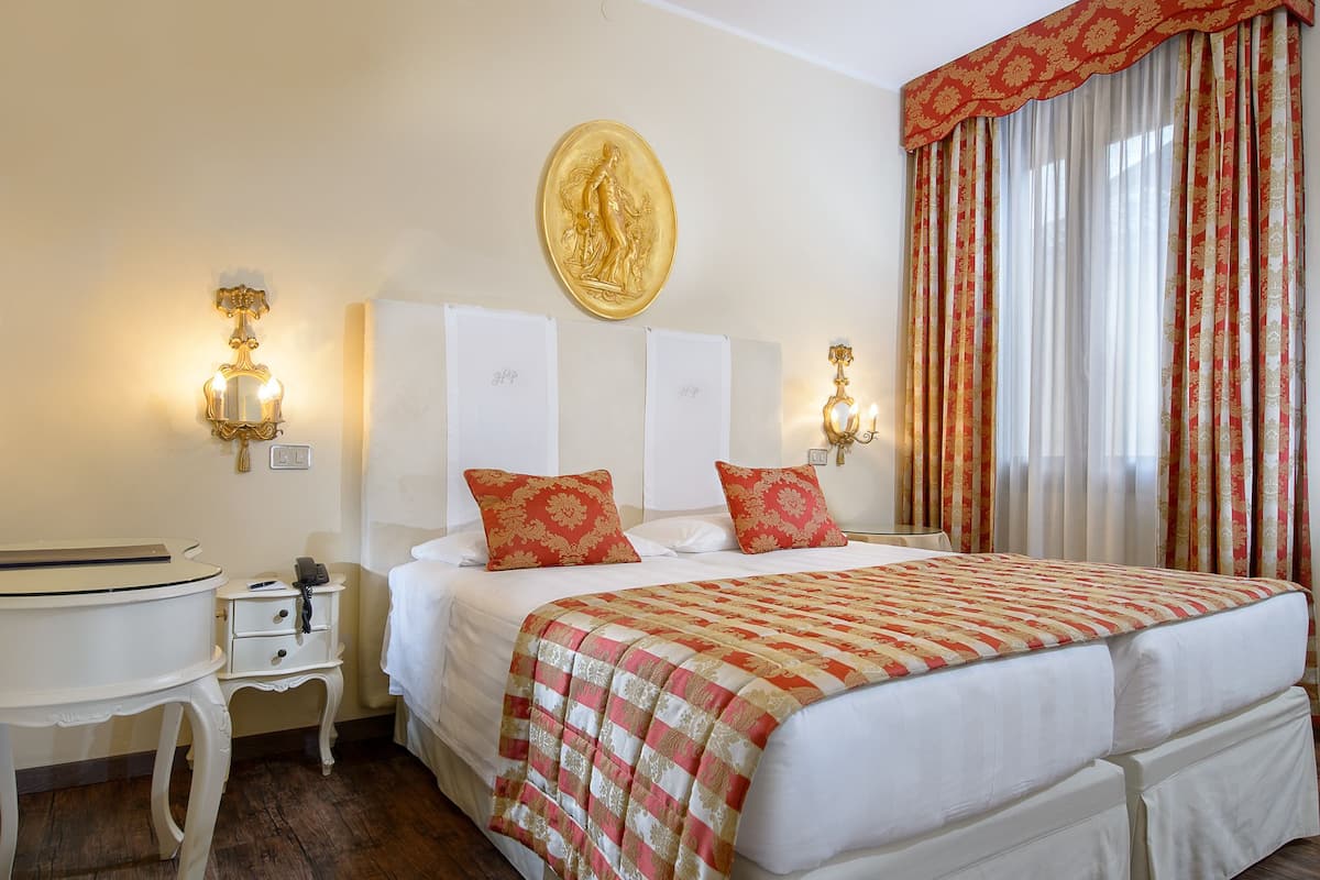 Une chambre d’hôtel avec un grand lit, deux tables de chevet, un bureau et une œuvre d’art accrochée au mur.