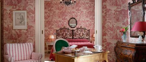 Una stanza con un letto, una sedia, un tavolo e uno specchio.