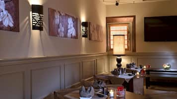 Un comedor con una mesa larga, varias sillas, obras de arte colgadas en la pared y un televisor.