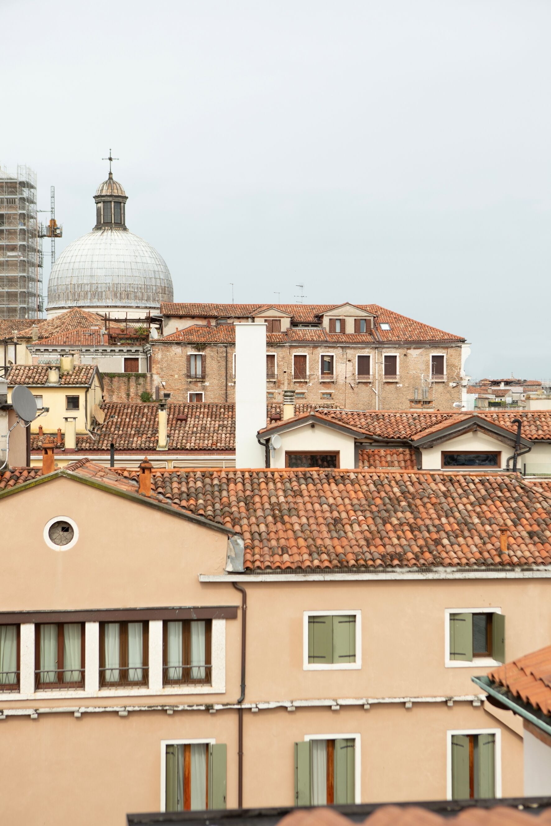 A view of a cityscape with traditional buildings, a dome structure, and a construction crane.