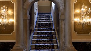 Una imponente escalera con candelabros ornamentales y un diseño arquitectónico clásico.