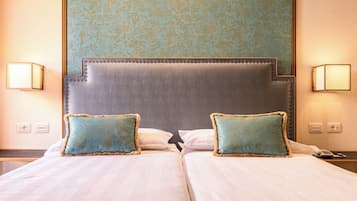 Una cama doble con dos almohadas, un cabecero y dos lámparas fijadas a la pared.