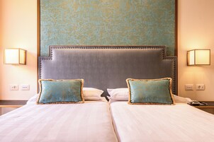 Una cama doble con dos almohadas, un cabecero y dos lámparas fijadas a la pared.