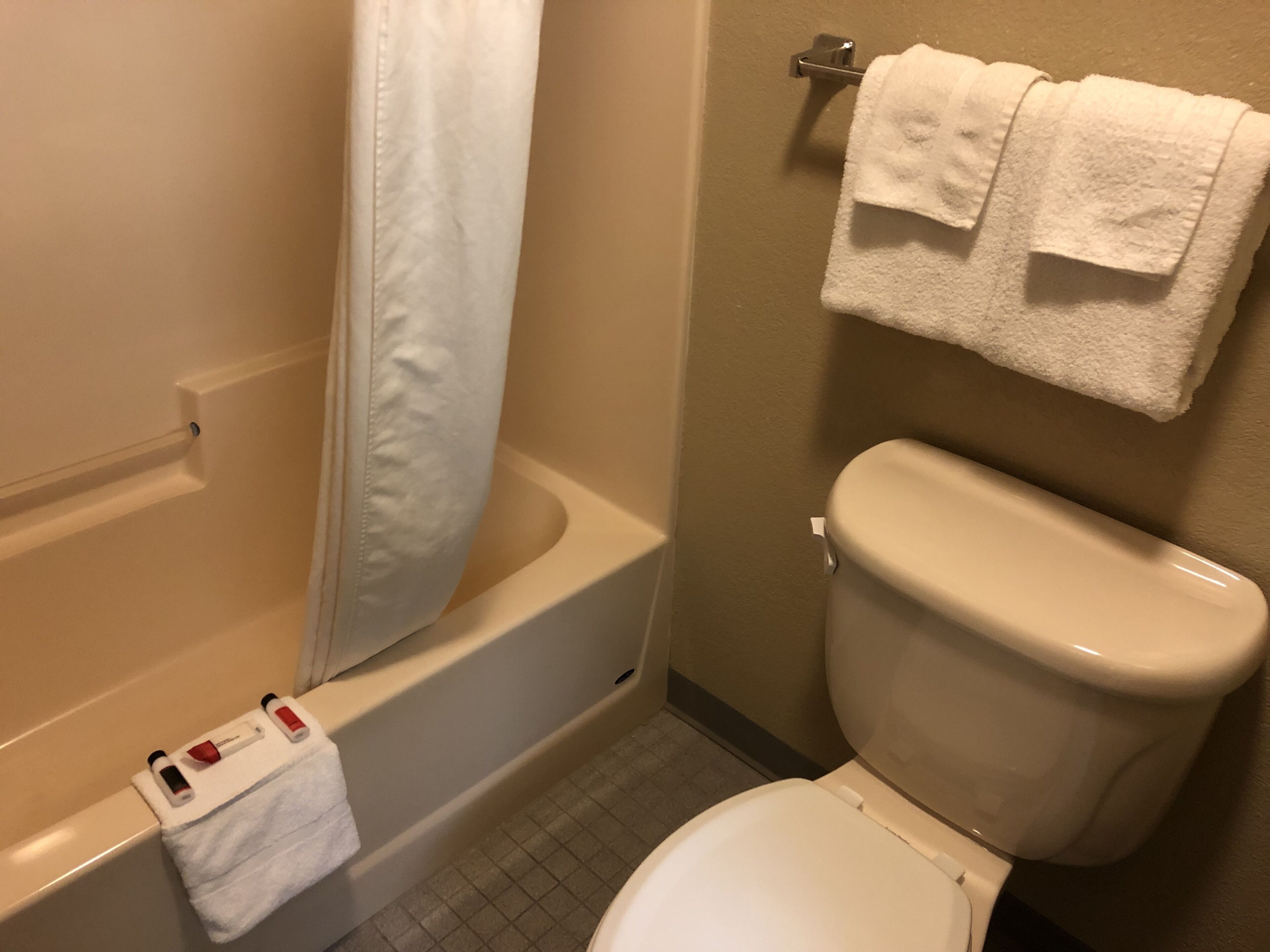 A bathroom with a bathtub, toilet, and a towel rack with two towels.