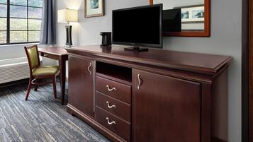 Habitación de hotel con un escritorio de madera, televisor, silla y ventana con vistas al exterior.