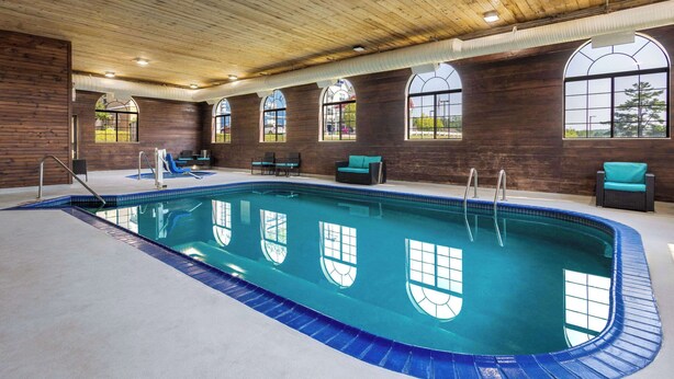 An indoor swimming pool with a wooden ceiling, large windows, and a tiled floor. - Days Inn by Wyndham Iron Mountain (Iron Mountain)
