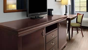 Un escritorio de madera oscura con un televisor de pantalla plana, una lámpara y una silla.