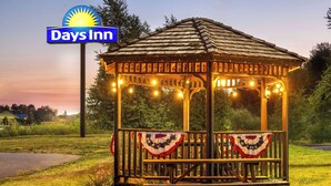 A gazebo with a Days Inn sign, surrounded by greenery and string lights. - Days Inn by Wyndham Iron Mountain (Iron Mountain)