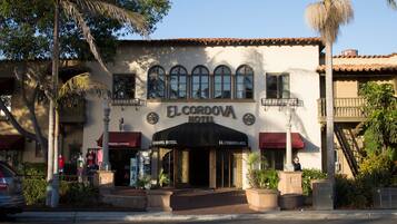 The exterior of El Cordova Hotel with a traditional facade, large arched windows, and a red awning.