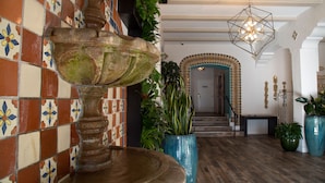 Eine Lobby mit einer Steinfountain, gefliesten Wänden und einer Treppe.