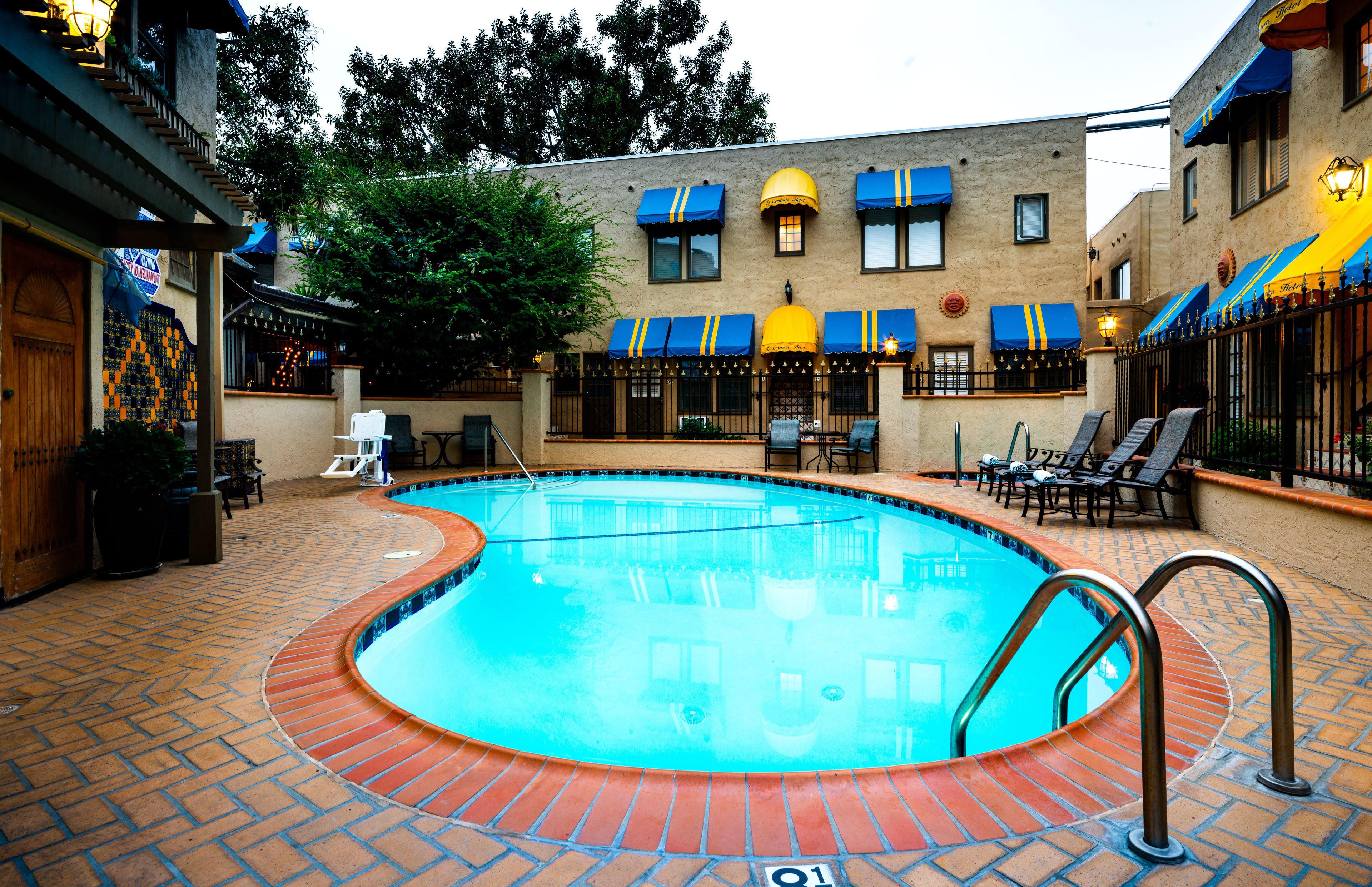 A swimming pool with a brick border, surrounded by lounge chairs and a brick patio.