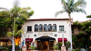 Das El Cordova Hotel mit einem gefliesen Dach, Bogenfenstern und einer roten Markise.