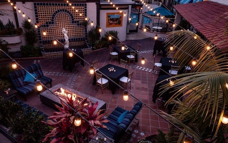 An outdoor patio area with string lights, seating arrangements, and a fire feature.