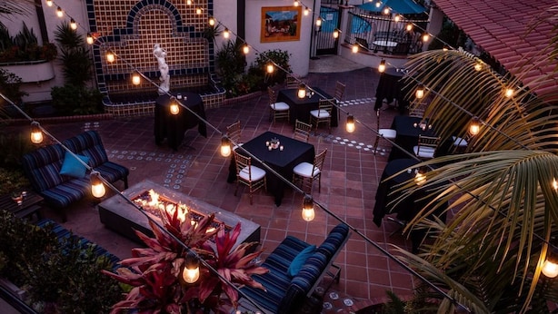 Ein Terrassenbereich im Freien mit Lichterketten, Sitzgelegenheiten und einer Feuerstelle.