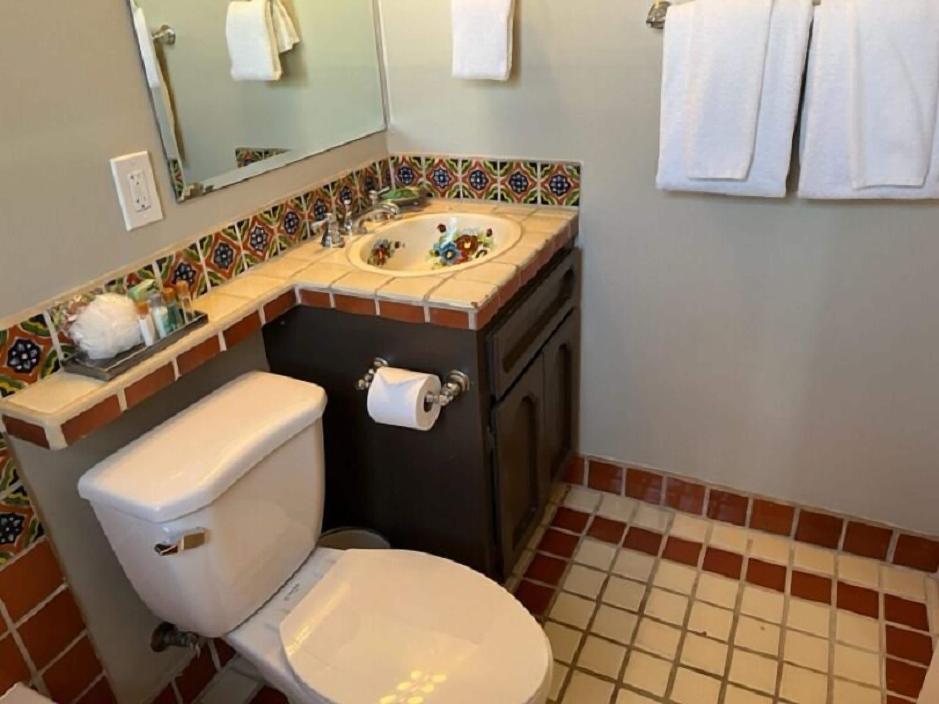 Een badkamer met toilet, wastafel en spiegel.