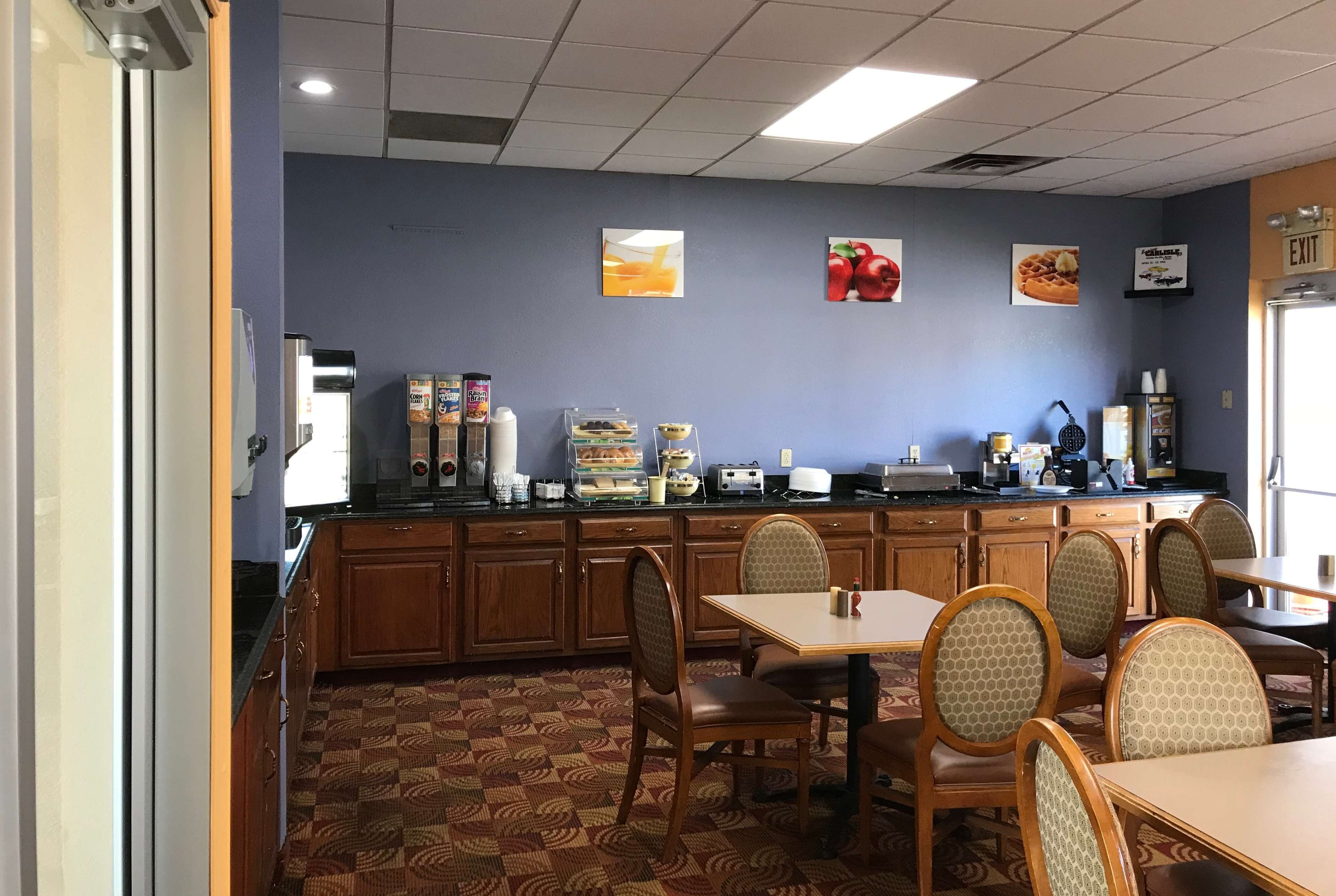 A restaurant with wooden cabinets, a patterned floor, and a counter with food items and condiments.