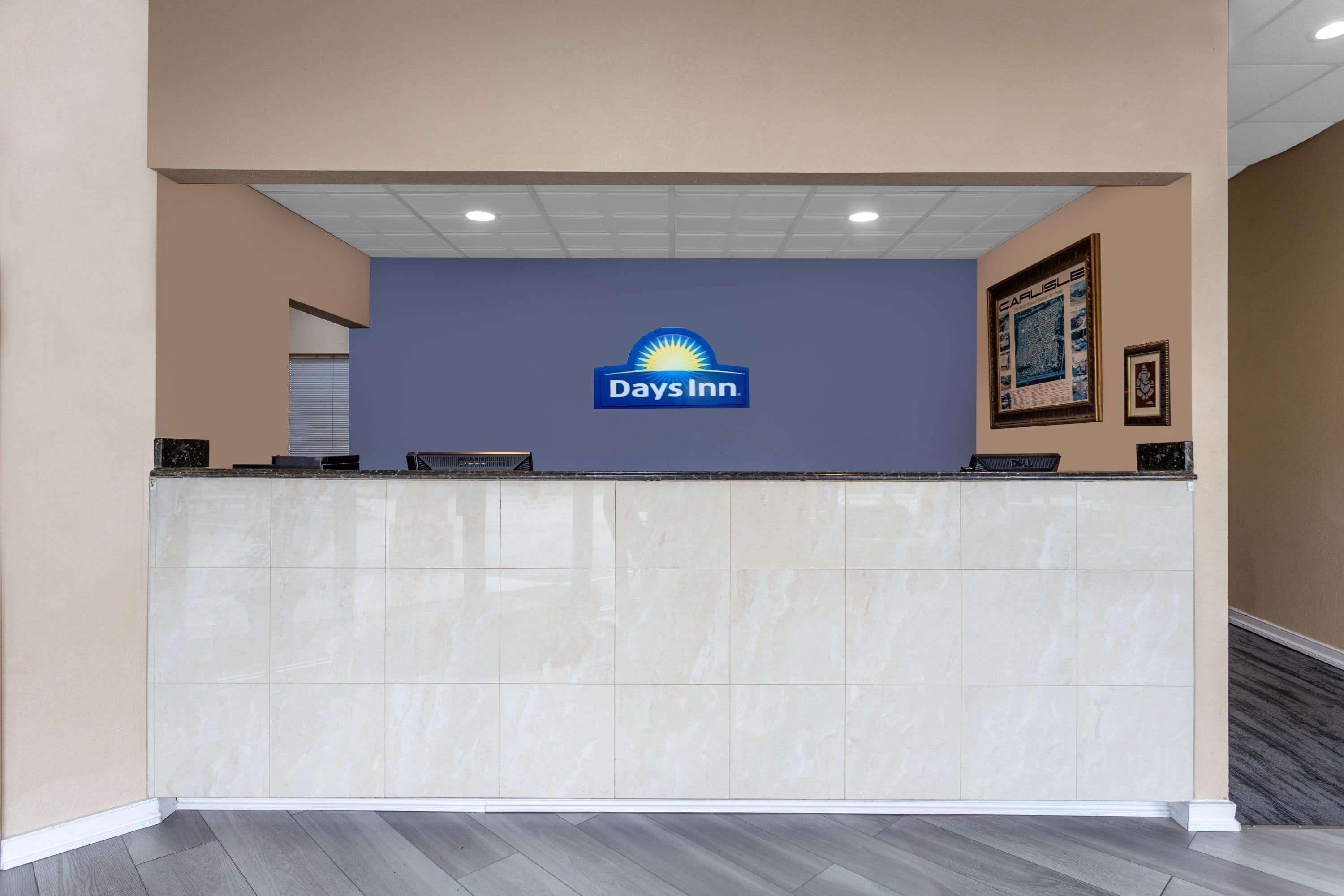 A reception desk with a Days Inn logo, a tiled counter, and a framed picture on the wall.