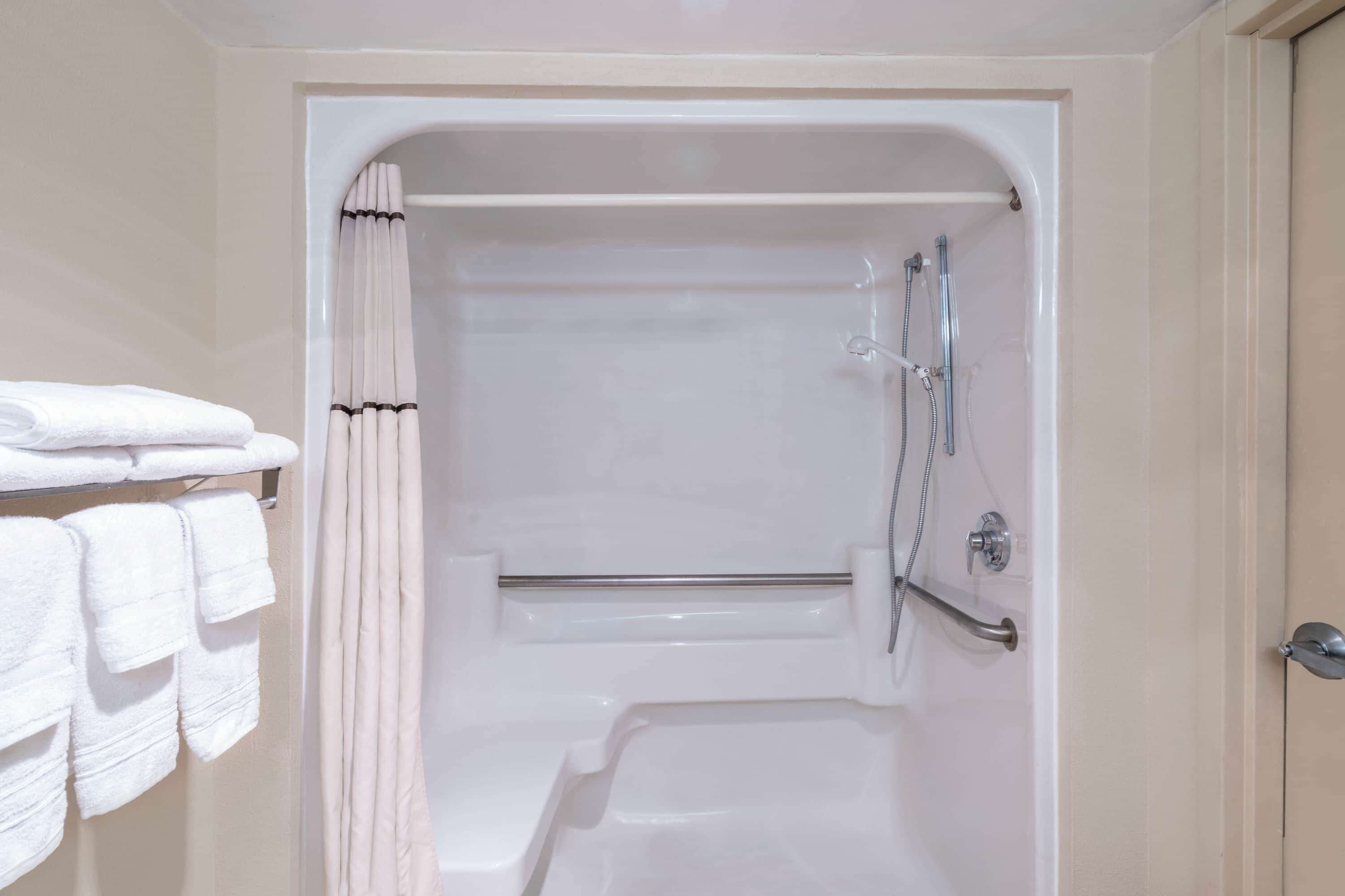A bathroom with a bathtub, a shower, and a towel rack with folded towels.