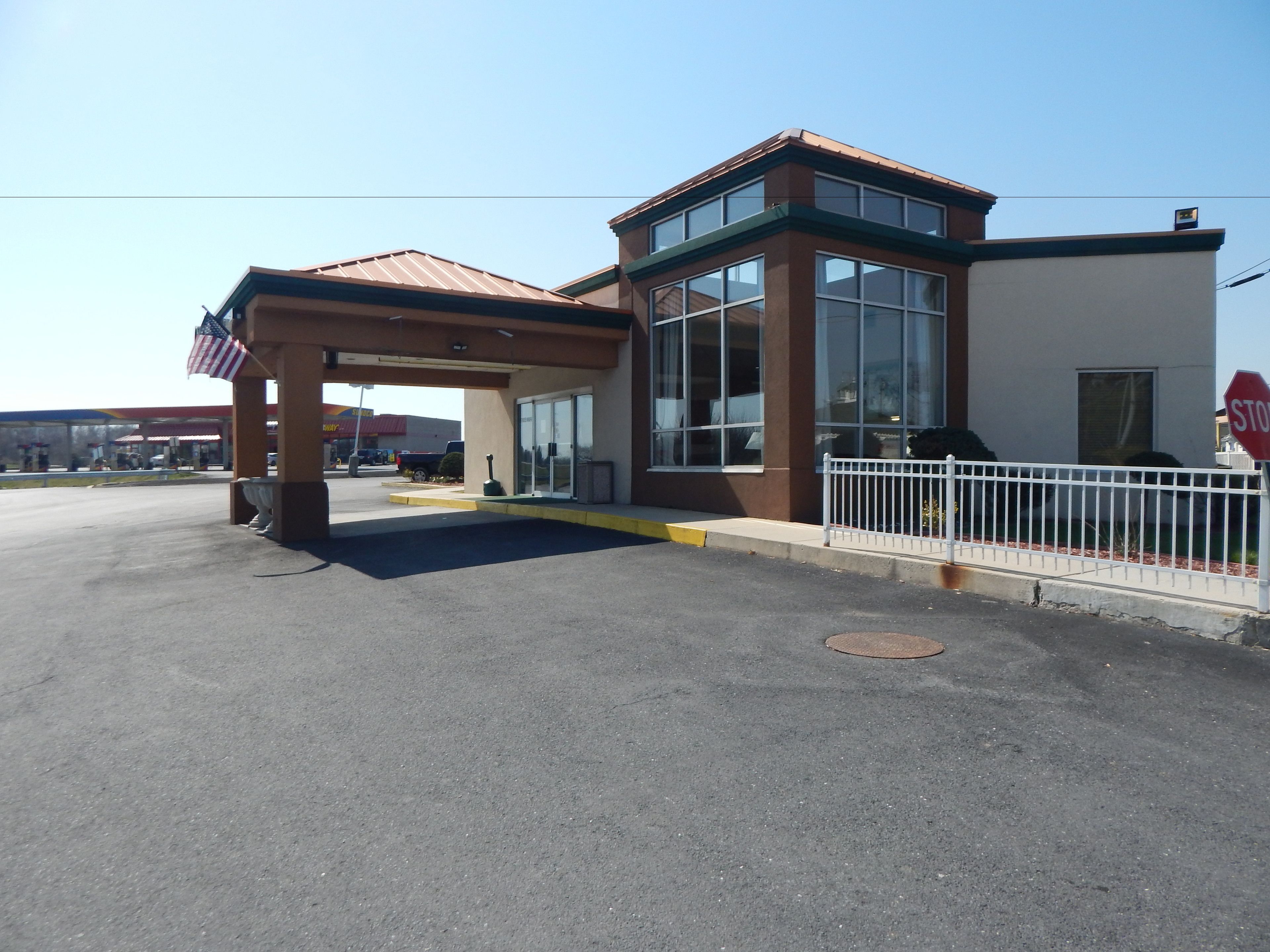 A building with a covered entrance, large windows, and a stop sign.