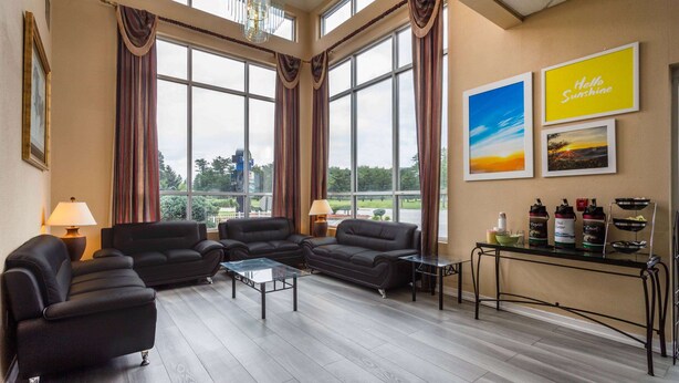 A spacious living room with large windows, a sofa set, a coffee table, and a small side table. - Days Inn by Wyndham Carlisle North (Carlisle)