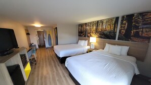 A hotel room with two beds, a desk, a television, and a painting of a forest on the wall. - Days Inn by Wyndham Carlisle North (Carlisle)
